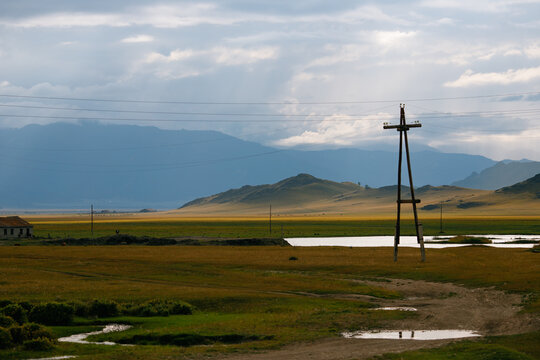Rural landscape with power lines and rolling hills under dramatic sky