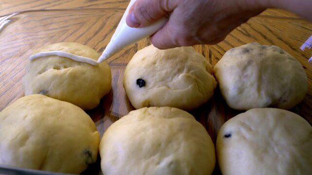 Decorate the bun with a religious cross made of flour. Hot Cross Buns  close‑up,  brioche de Vendredi Saint, mazanec, Good Friday, Easter tradition. Step-by-step preparation of homemade traditional Ea
