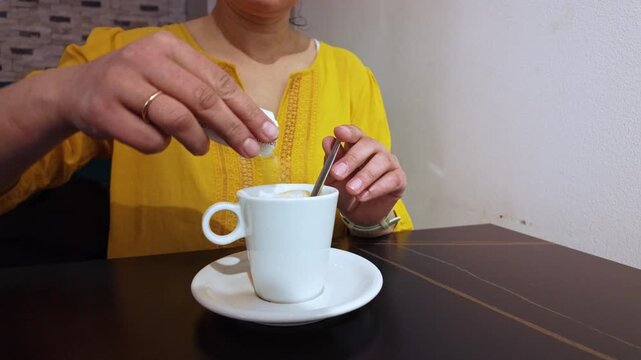 Woman Adding Sugar to Coffee and Stirring Her Drink at a Cafe