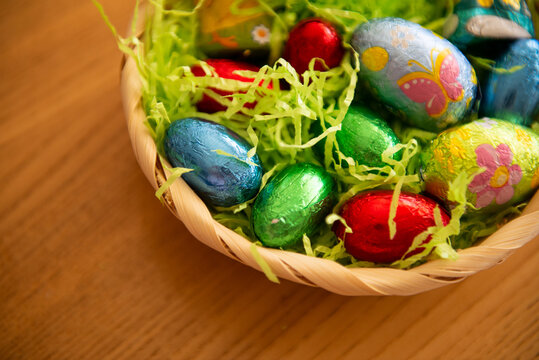 Chocolate Easter eggs in colored foil lie in a basket