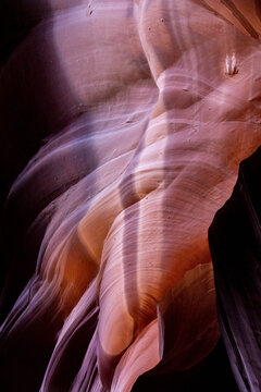 View of light and shadow dance on the undulating, textured sandstone walls of a slot canyon, creating a mesmerizing natural sculpture, Page, Arizona, United States.