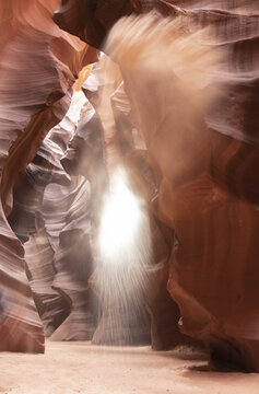 View of ethereal light piercing through the undulating, sandstone walls of a slot canyon, creating a mesmerizing display of light and shadow, Page, Arizona, United States.