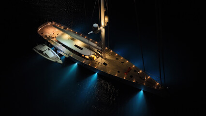 Aerial drone night shot of illuminated sail boat with wooden deck anchored in deep blue Aegan sea © aerial-drone