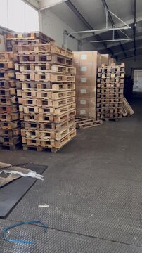 A wide shot inside a warehouse showing neat stacks of wooden pallets and large boxes wrapped in plastic, ready for shipping or storage