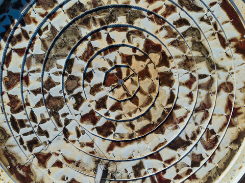 Aerial view of concentric circles of geometric patterns create a mesmerizing mosaic, their earthy tones contrasting with the stark white grout, Kalochori, Thessaloniki, Greece.