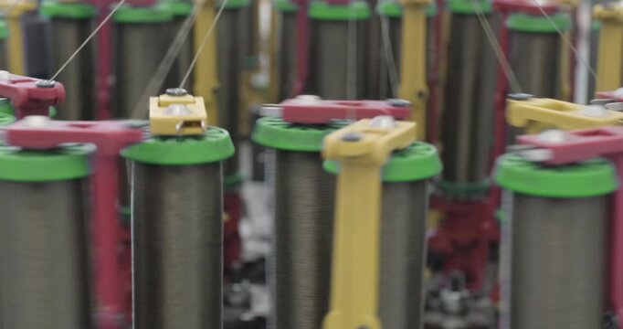 Braiding equipment, machine for weaving ropes, cables or wires is working, bobbins are moving. Close-up handheld shot, real time speed.