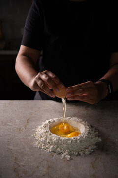 Cracking egg over dough 