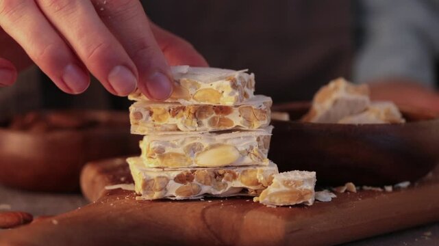A close-up video of stacked pieces of traditional Spanish Turron de Alicante, a hand puts the last piece to the top , almond nougat made with honey and egg whites