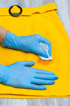 A woman removes a stain from her skirt. A woman's hand holds a stain remover to remove a dirty spot from a skirt. A greasy stain on a yellow skirt. Vertical photo