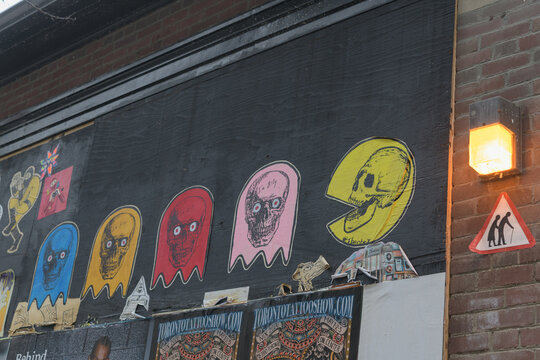 street art outside St Patrick's Market (Queen St W) area featuring posters (Toronto Tattoo Show NIX) and wheatpaste photocopy slap-ups with pacman theme