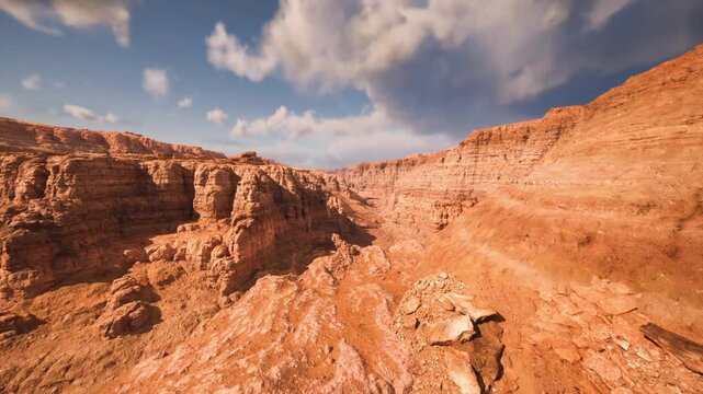 Wide red canyon landscape under patchy sky revealing layered strata and erosion patterns, foreground scree and rocky outcrops ideal for geological study