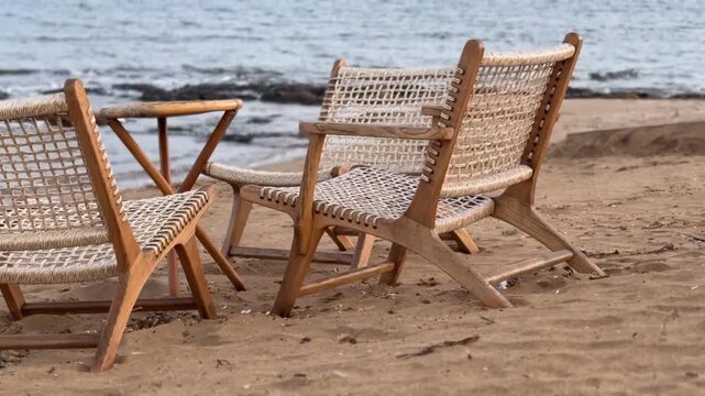 Beach chairs on sandy shore facing ocean, woven backrest design, serene vacation background