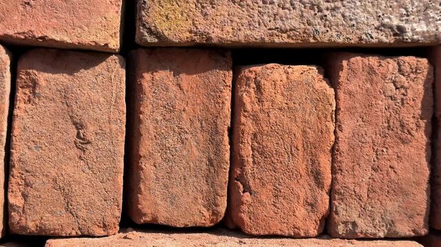 Close-up of stacked red bricks forming a textured wall background with natural patterns