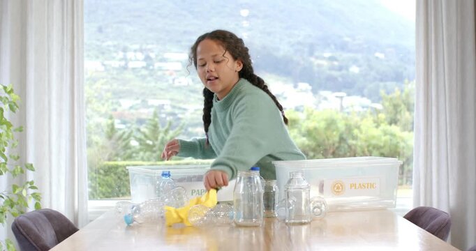Female child entering dining area sorting items for recycling into Paper, Plastic and Glass bins