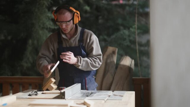 A skilled carpenter precisely cuts a piece of wood using a table saw while wearing safety gear. The woodworker focuses on his craft, ensuring accurate cuts in a workshop setting.