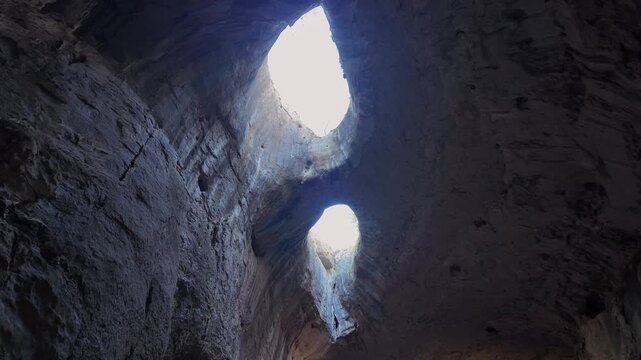 Inside view looking up at the Eyes of God, two large, eye shaped openings in the ceiling of Prohodna Cave, a famous landmark in Bulgaria