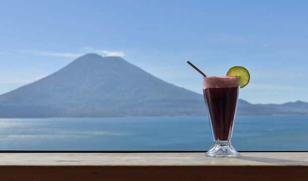 Beverage with lime garnish set against a scenic lake atitlan and volcano backdrop, relaxation and travel lifestyle smoothie