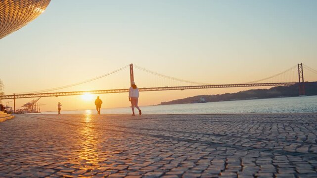 People jogging and walking on lisbon promenade at sunset