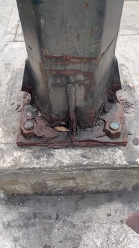 Close-up of Heavily Corroded, Weak Metal Post Base on Concrete