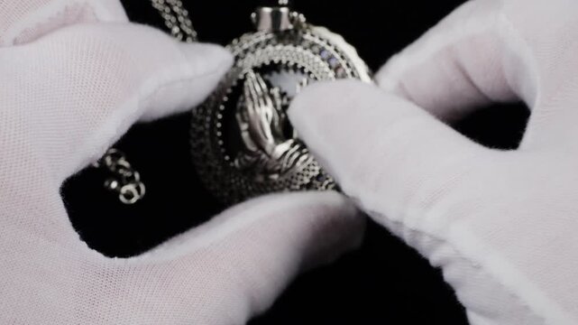 The piece features praying hands with a cross inside an ornate openwork frame. This macro shot highlights the fine craftsmanship and spiritual symbolism of the jewelry.