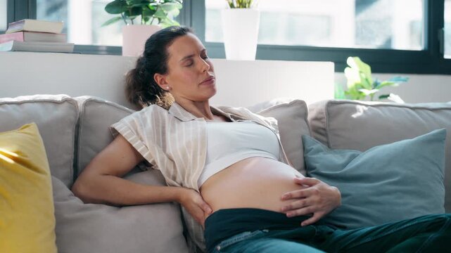 Video of pregnant woman with back pain and sciatica sitting on the couch at home