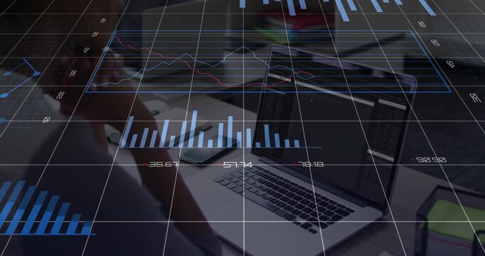 Man sitting at desk watching laptop while live data feed updating and animating charts for business