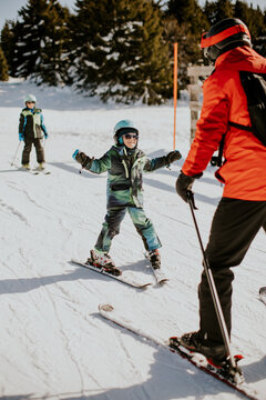 Child learning to ski with instructor on snowy slope at winter resort in daytime