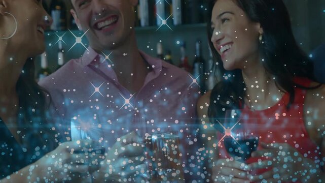 3 adults toasting wine glasses at bar, camera shifting right cropping, sparkle overlay over bottles