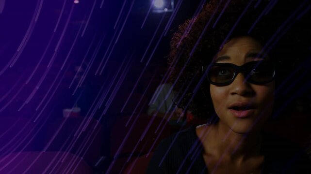 Woman wearing 3D specs sitting in purple-lit cinema, projector sweeping, eliciting responses