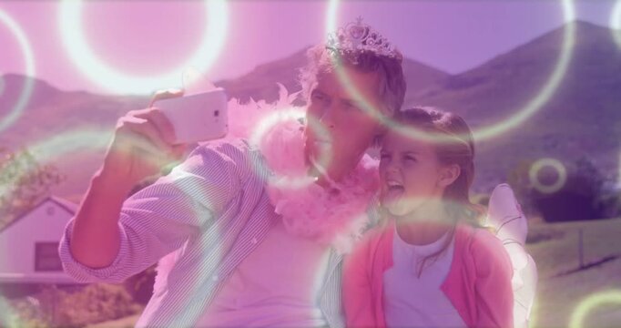 Vertical video: Reaching phone, man and girl taking selfie on bench with tiara boa wings pink rings