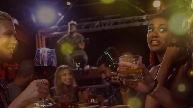 Musician starting acoustic song, friends clinking wine glass and tumbler, celebrating under bokeh