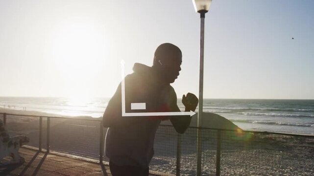 Vertical video: Shadowboxing man wearing hoodie, dark pants training by seafront railing, chart