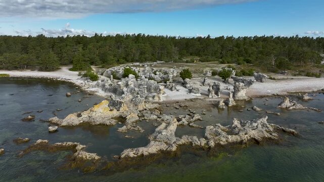 Top-down drone view of waves crashing over rocky limestone coastline in Gotland, Sweden with Baltic Sea water forming foam and patterns