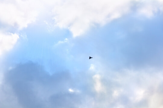 Shahed type kamikaze drone flying in blue sky with clouds, black loitering munition, unmanned aerial vehicle (UAV) in flight