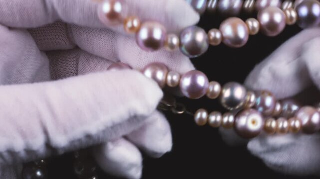 The jewelry features high-quality natural freshwater pearls in soft pink and lavender shades. Elegant close-up shot showing the smooth texture and iridescent glow of the precious beads.