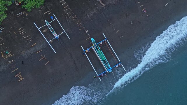 Balinese fishermen launching a traditional jukung boat from amed beach