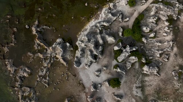 Top down drone shot ascending over limestone sea stacks and rocky coastline at Folhammar raukf&auml;lt, Gotland, Sweden along the Baltic Sea revealing wider landscape