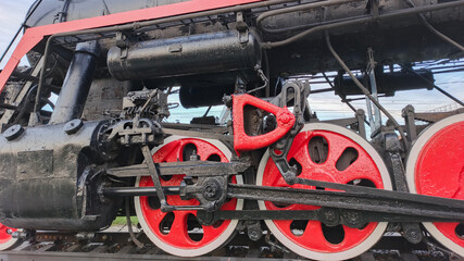 An antique steam locomotive with transmission and red wheels © Sergei