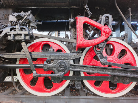 An antique steam locomotive with transmission and red wheels