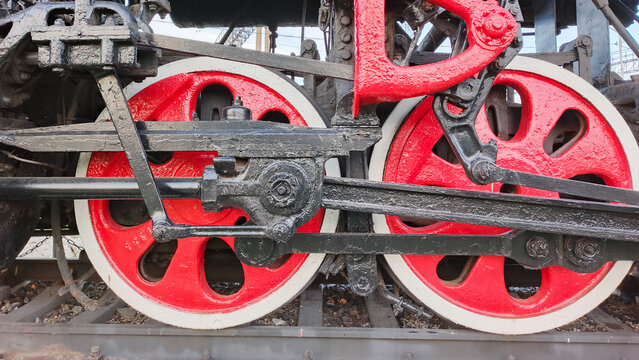 An antique steam locomotive with transmission and red wheels