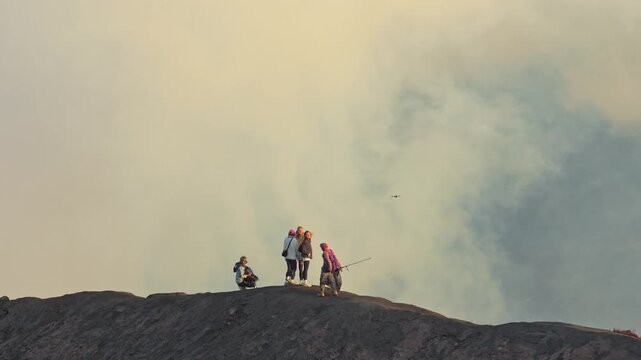 Small group of people hiking on the mount bromo volcano crater rim