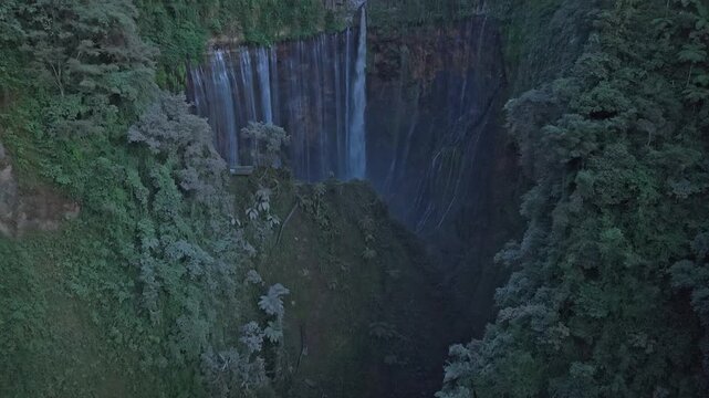 Tumpak sewu waterfall flowing in a canyon with semeru volcano in the background
