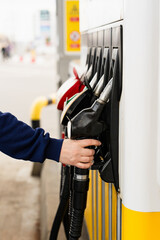 Hand holding gasoline nozzle at fuel station during car refueling. © Rabizo Anatolii