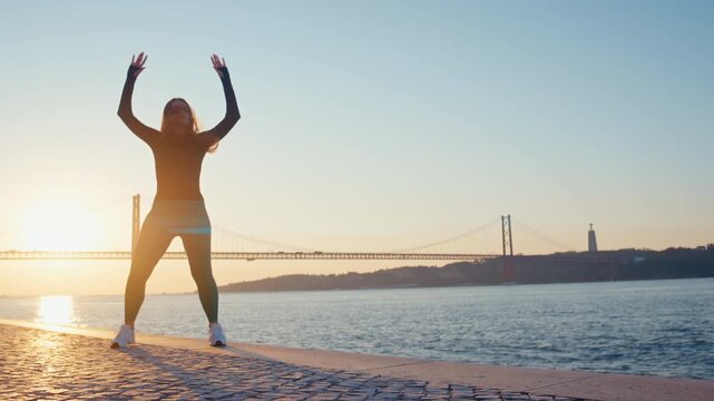 Energetic woman doing jumping jacks at sunrise