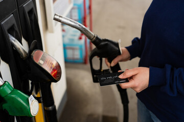 Card held near petrol pump nozzle while refueling vehicle. © Rabizo Anatolii