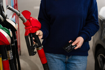 Hand holding bank card near gasoline nozzle during refueling. © Rabizo Anatolii