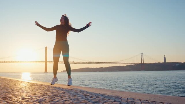 Woman doing jumping jacks exercise at sunrise in lisbon