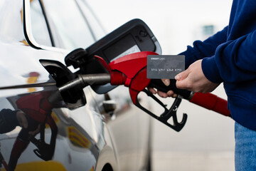 Close-up of bank card near gasoline nozzle at gas station. © Rabizo Anatolii