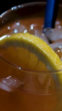 Glass of apperol spritz cocktail with orange slice and straw on blue background. Closeup of summer drink, zoom out. High quality 4k footage