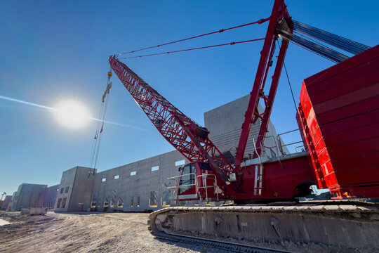 Heavy duty high-capacity lattice-boom crawler, crane parked at warehouse construction site, used for lifting large and heavy precast concrete wall panels 